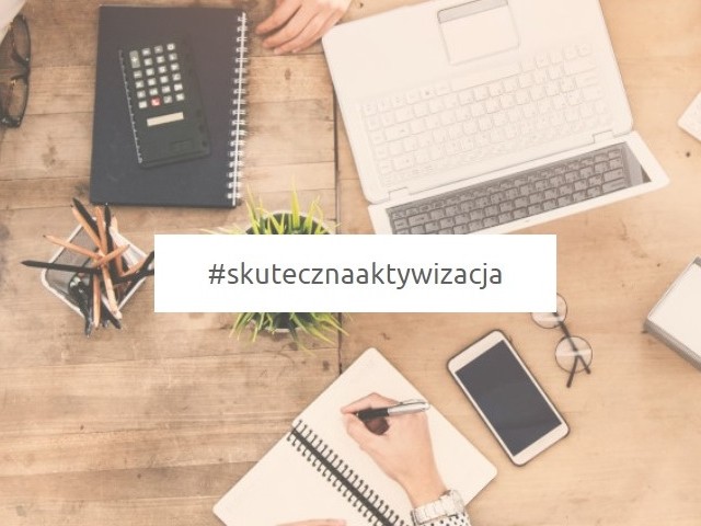 Widok z góry. Na blacie leży laptop, notes, telefon komórkowy