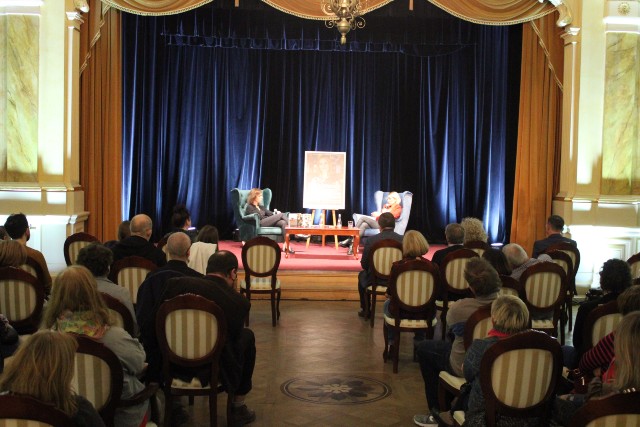 Sala pełna publiczności, na drugim planie scena